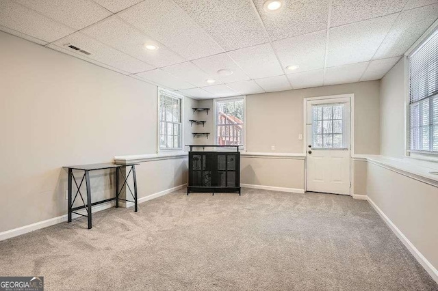 unfurnished room featuring carpet, a healthy amount of sunlight, visible vents, and baseboards