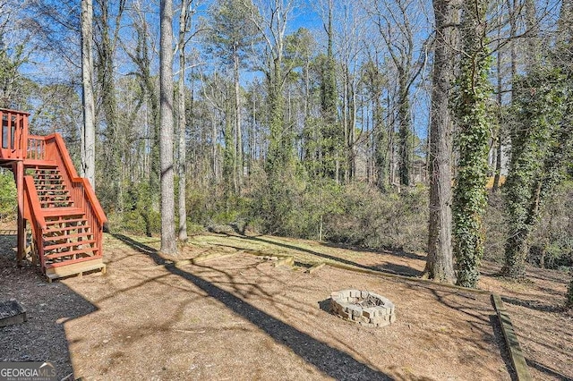 view of yard with an outdoor fire pit, stairway, and a view of trees