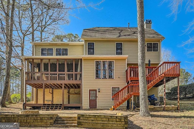 rear view of property featuring a chimney, a sunroom, stairway, and a deck