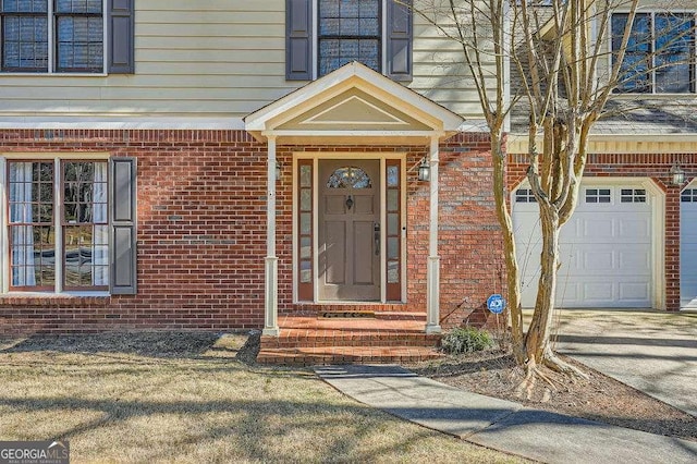 entrance to property with a garage and brick siding