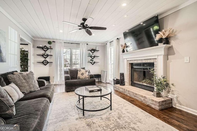 living room featuring ornamental molding, a brick fireplace, wood finished floors, and wood ceiling