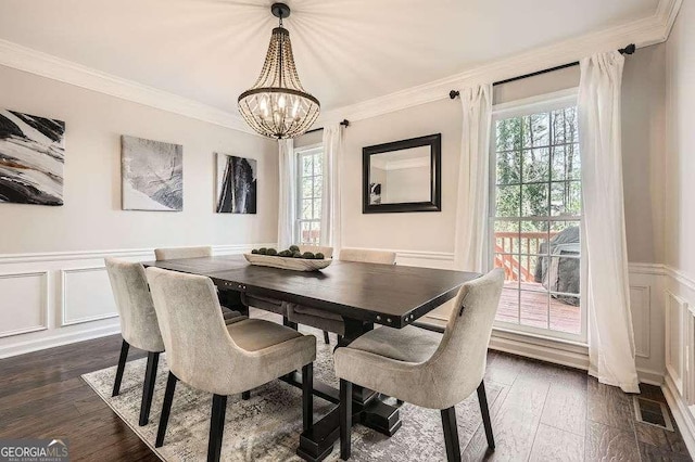 dining room with an inviting chandelier, ornamental molding, a decorative wall, and dark wood-style flooring