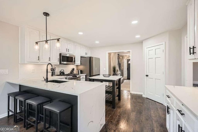 kitchen with dark wood-type flooring, a peninsula, stainless steel appliances, white cabinetry, and a sink