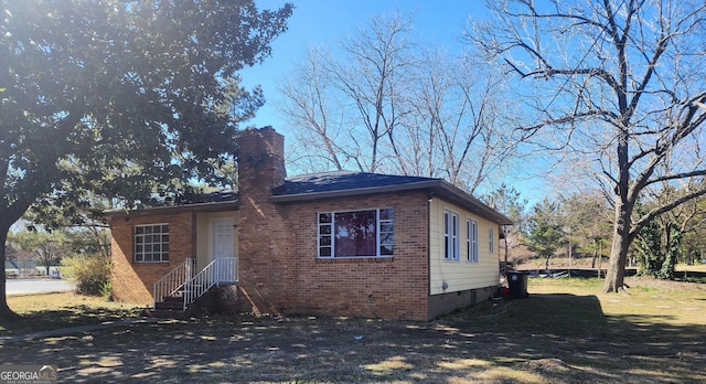 view of front of property with brick siding, crawl space, and a chimney