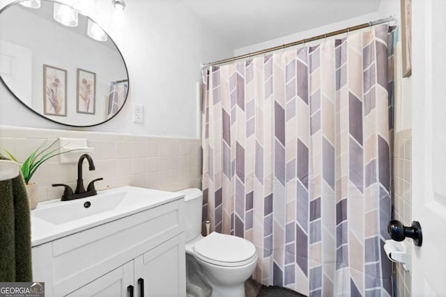 full bath featuring curtained shower, toilet, a wainscoted wall, vanity, and tile walls