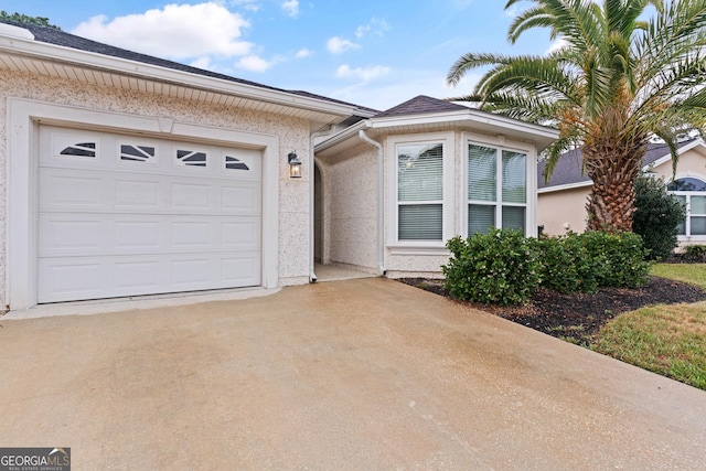 ranch-style house featuring concrete driveway, an attached garage, and stucco siding