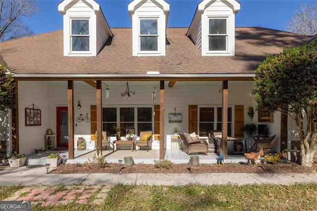 view of front facade with a patio area, roof with shingles, and outdoor lounge area