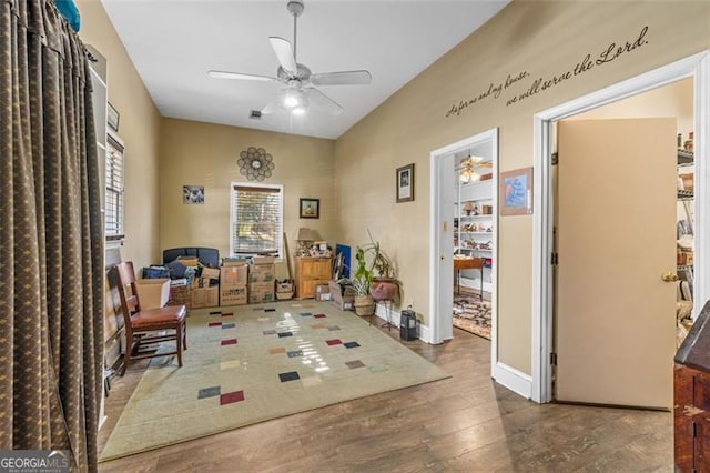 living area with ceiling fan, wood finished floors, a wealth of natural light, and baseboards