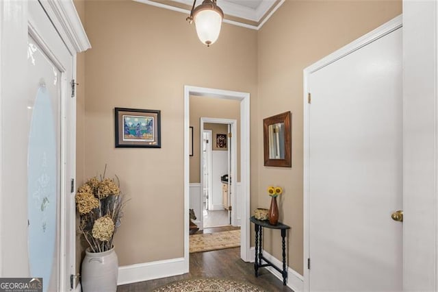 hallway featuring dark wood-style flooring, crown molding, and baseboards