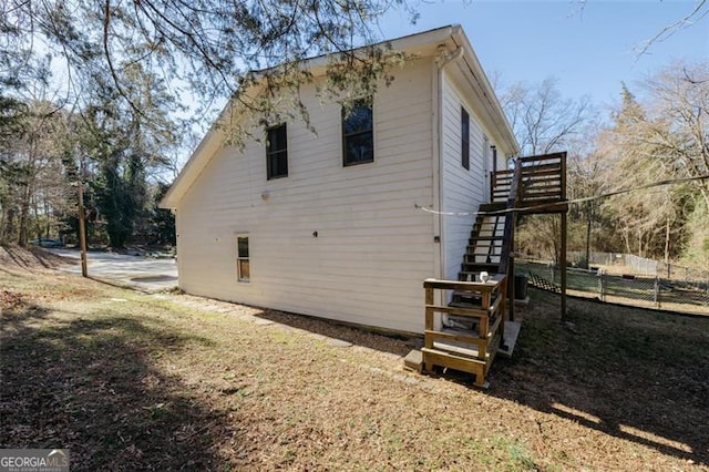 view of side of property featuring stairs and fence