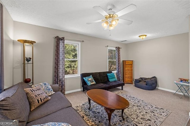 carpeted living room with ceiling fan, a textured ceiling, and baseboards