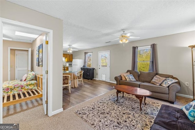 living room featuring a textured ceiling, ceiling fan, and baseboards