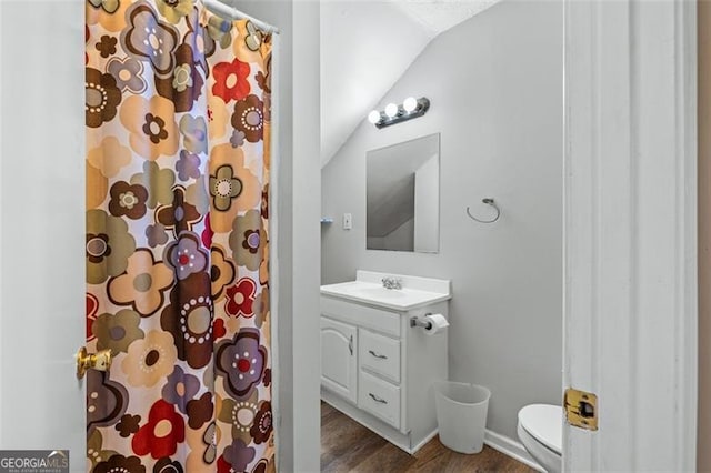 bathroom featuring lofted ceiling, toilet, a shower with shower curtain, wood finished floors, and vanity