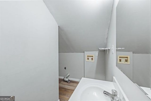 bathroom with lofted ceiling, a sink, baseboards, and wood finished floors