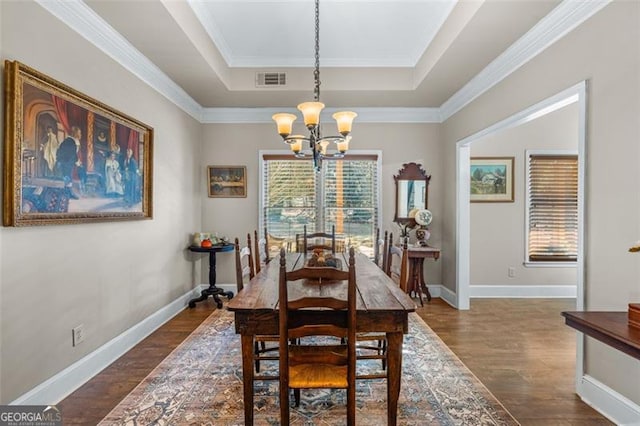 dining room featuring an inviting chandelier, a tray ceiling, dark wood-type flooring, and a wealth of natural light