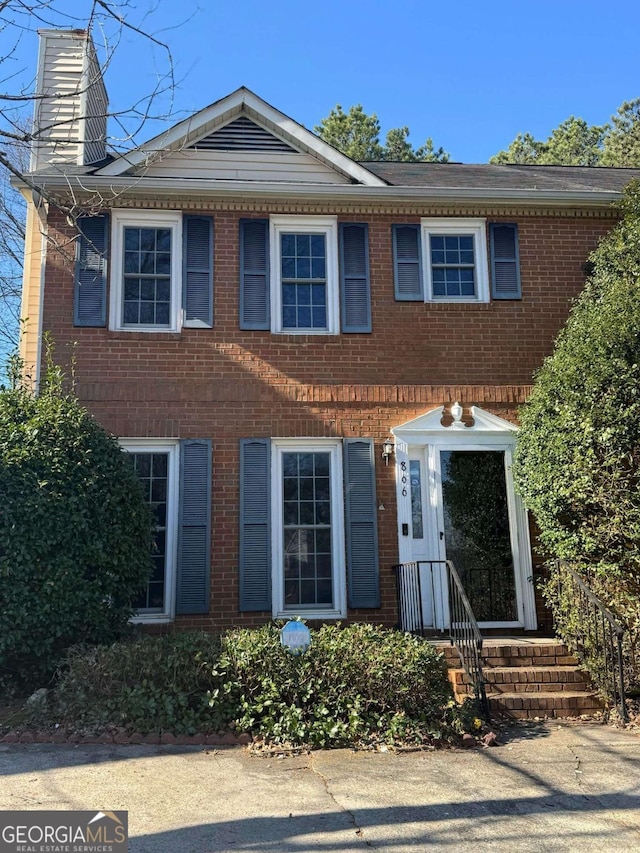 view of front of home with a chimney and brick siding