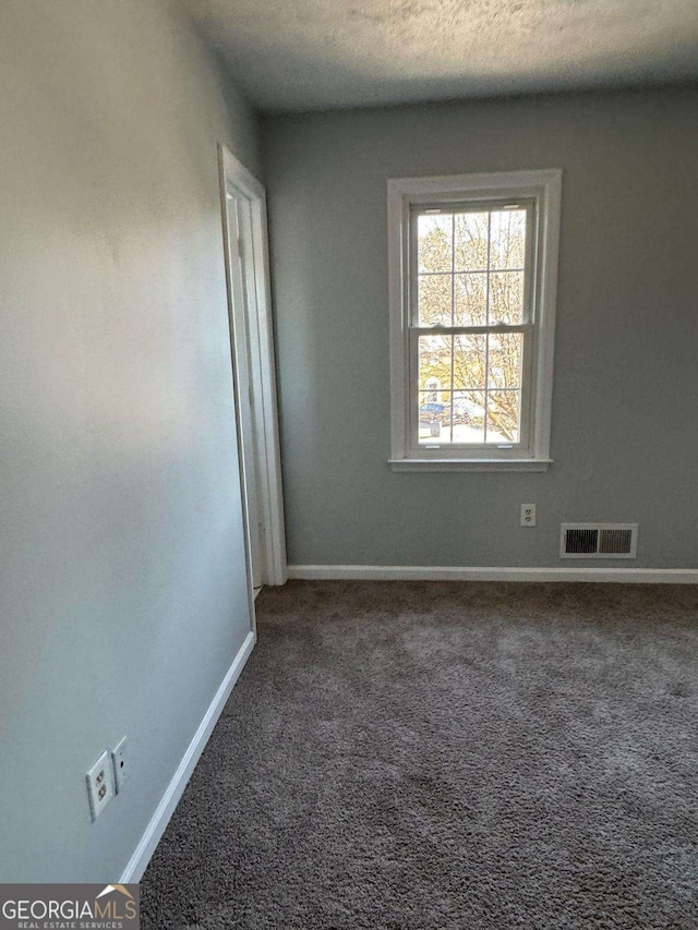 carpeted spare room with visible vents, a textured ceiling, and baseboards