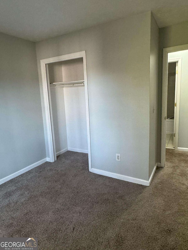 unfurnished bedroom featuring carpet floors, baseboards, and a closet