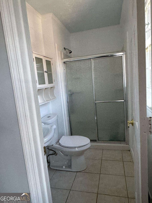 bathroom with toilet, a shower stall, and tile patterned floors