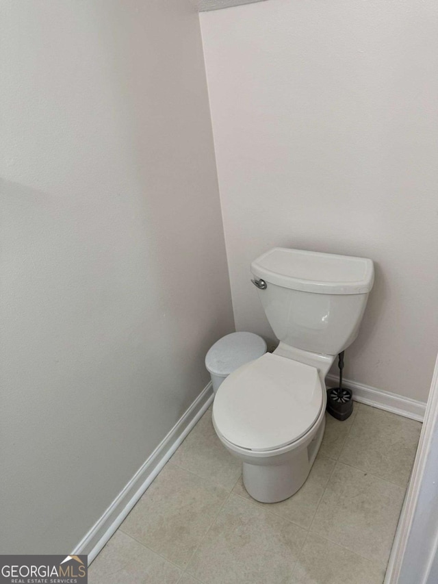 bathroom featuring tile patterned flooring, toilet, and baseboards