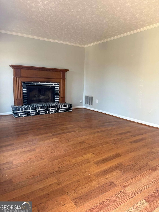 unfurnished living room with visible vents, a tiled fireplace, ornamental molding, wood finished floors, and a textured ceiling