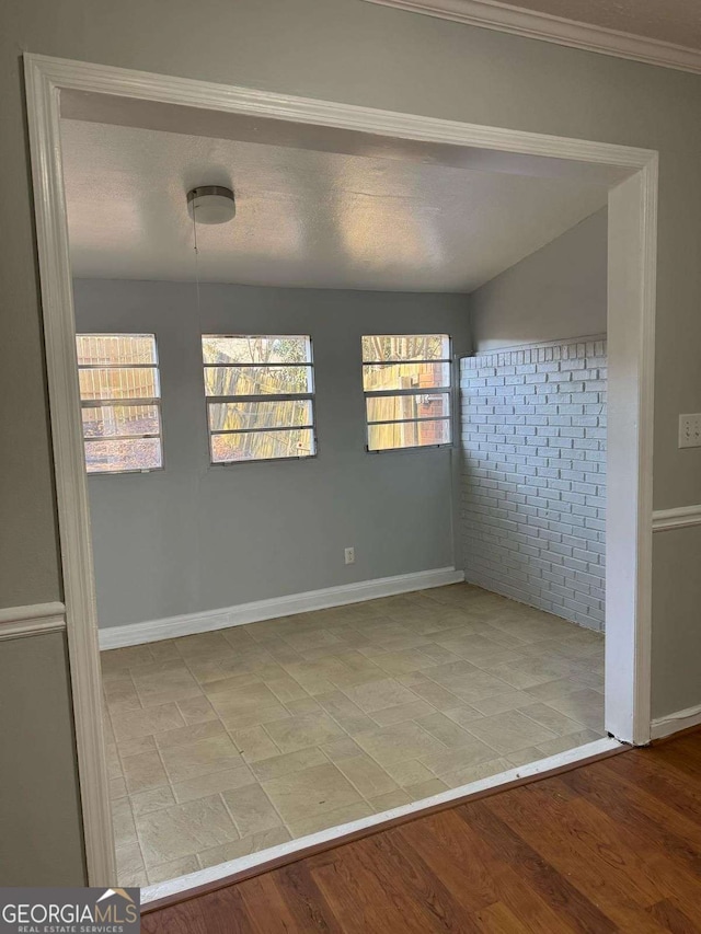 spare room with a textured ceiling, baseboards, and wood finished floors