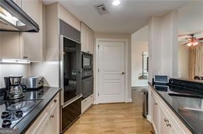 kitchen featuring black appliances, dark countertops, visible vents, and under cabinet range hood