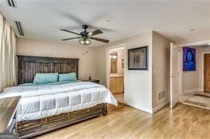 bedroom with ceiling fan, wood finished floors, visible vents, and connected bathroom