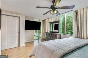 bedroom featuring ceiling fan, multiple windows, and wood finished floors