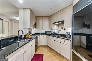 kitchen featuring a sink, dark countertops, exhaust hood, and light wood-style floors