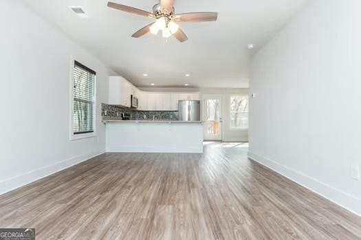 unfurnished living room featuring a ceiling fan, baseboards, and wood finished floors