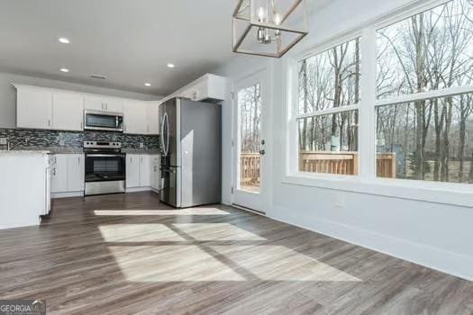 kitchen with dark wood finished floors, white cabinetry, stainless steel appliances, and backsplash