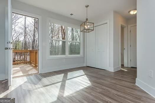 unfurnished dining area with a chandelier, baseboards, and wood finished floors