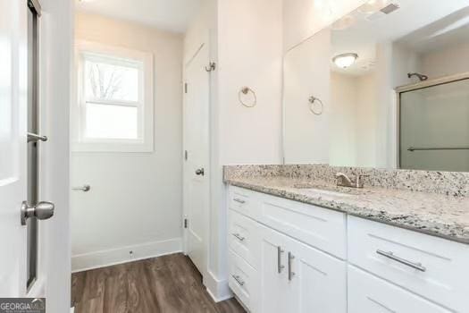 full bath featuring an enclosed shower, wood finished floors, vanity, and baseboards