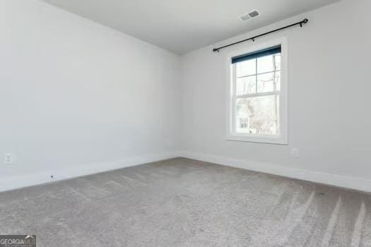 carpeted spare room with visible vents and baseboards