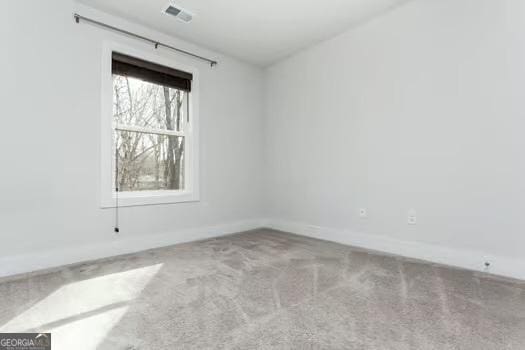 unfurnished room with carpet, visible vents, and baseboards