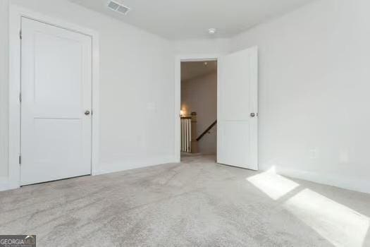 unfurnished bedroom featuring carpet and visible vents