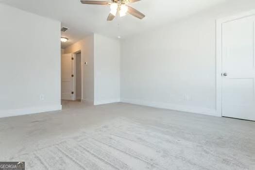 empty room featuring baseboards, a ceiling fan, visible vents, and light colored carpet