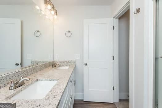 full bath featuring double vanity, a sink, and wood finished floors