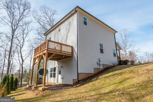 back of house featuring a deck and a lawn