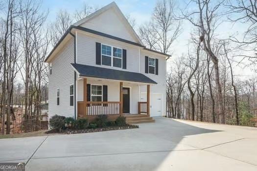 view of front facade with an attached garage, a porch, and concrete driveway