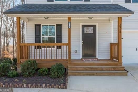 doorway to property with a porch and a shingled roof