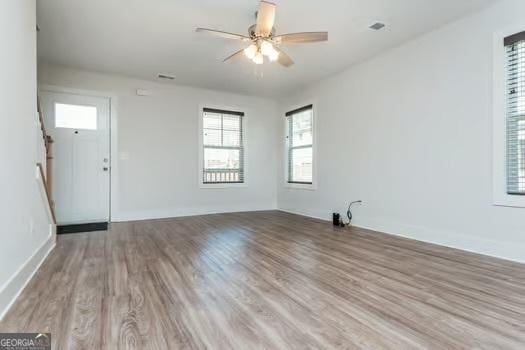 unfurnished living room with ceiling fan, baseboards, and wood finished floors