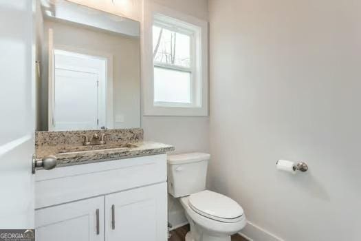 bathroom featuring toilet, baseboards, and vanity