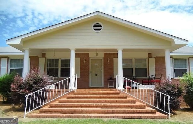 bungalow-style home with covered porch and brick siding