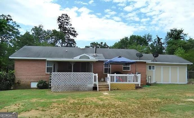 rear view of house featuring a sunroom, brick siding, a deck, and a yard