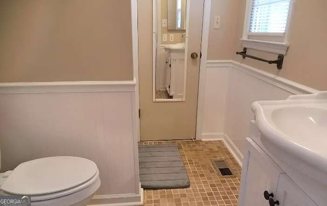 bathroom featuring toilet, wainscoting, and vanity