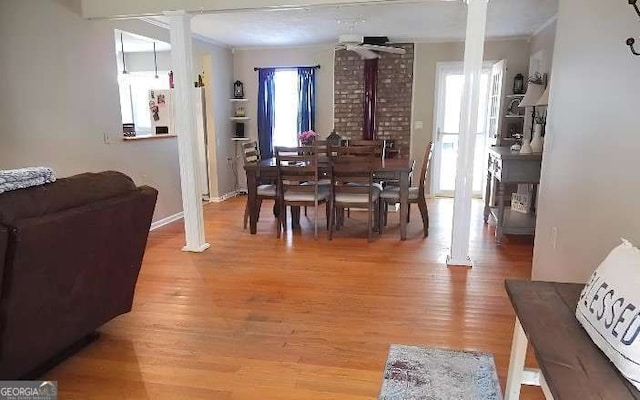 dining area with light wood-type flooring, a ceiling fan, and ornate columns