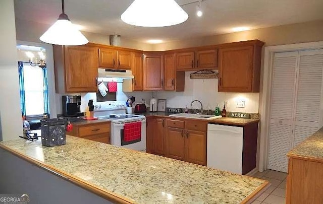 kitchen with white appliances, a peninsula, light countertops, under cabinet range hood, and a sink