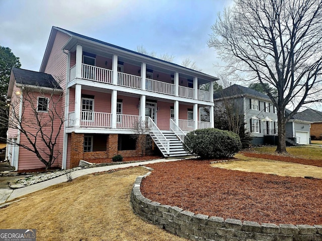 view of front of property with a porch, brick siding, a balcony, and a front lawn